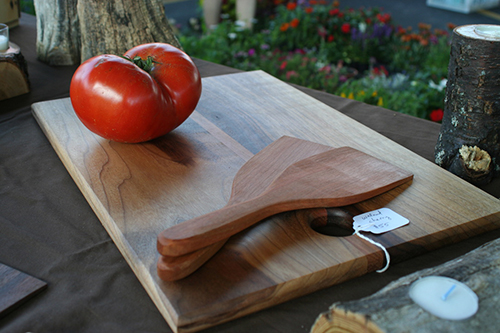 Close up of a tomato on a wooden cutting board with wooden spatulas